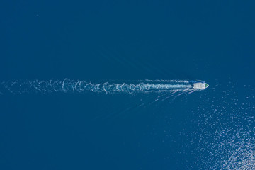 Top view of a white boat sailing to the blue sea
