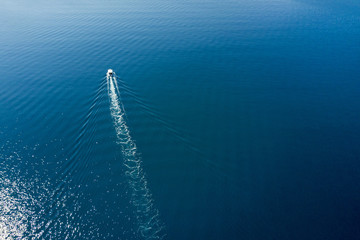 Top view of a white boat sailing to the blue sea