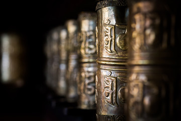 Buddhist prayer wheels in Tibetan monastery with written mantra. Temisgam monastery, Ladakh, India,...