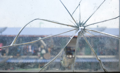 Close-up of a cracked glass window with an urban scene in the background, symbolizing fragility and urban decay.