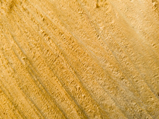 Close-up of a yellow wall with a rough, textured surface, highlighting its natural lines and patterns, perfect for backgrounds or design elements.