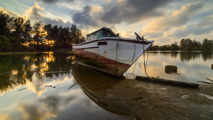 Fototapeta premium abandoned big old traditional boat with reflection at Seberang Marang, Terengganu, Malaysia in sunset