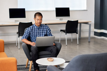 Young Asian designer working on a laptop in an office
