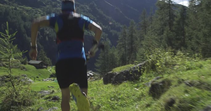 caucasian trail runner running in mountain through woods, villages. 4k gimbal wide back video shot