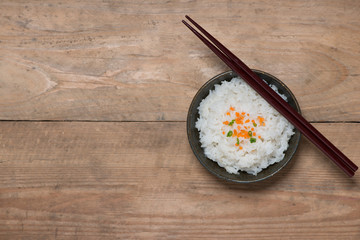 Boiled rice in a bowl on wooden table.