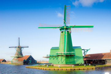 Scenic picture of the water and windmills in Zaanse Schans, Holland, Europe against the backdrop of a cloudy sky.