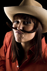 Portrait of young and attractive woman in red shirt and hat isolated on black background. She is having fun.