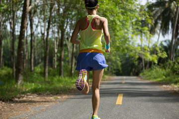 Young fitness woman running on morning tropical forest trail