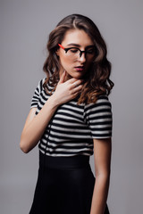 Smiling woman posing with glasses over the grey background