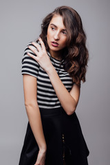 Emotive portrait of a fashionable model with curly hair and natural make-up posing over grey background.