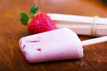 Homemade strawberry ice lolly on rustic background