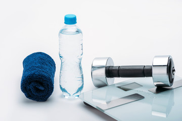 metallic dumbbell, scales, towel and bottle with water isolated on white. drink water, equipment sport and healthy living concept