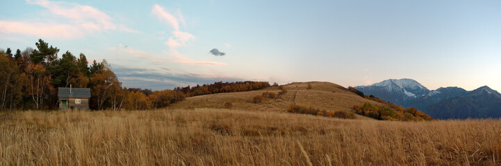 Autumnal subalpine landscape at sunset with snowy mountain peaks, forest, and meadow. Caucasus. Russia. The Caucasian reserve. Pasture Abago