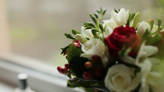 Beautiful wedding bouquet with red and white roses. Fresh wedding flower bouquet near the window. Bridal wedding bouquet. Close up shot