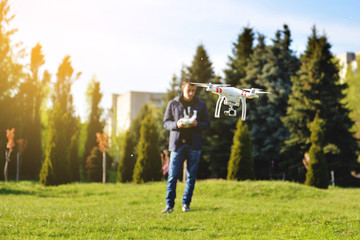 Man controls a quadrocopter. Selective focus on drone, men is blurred
