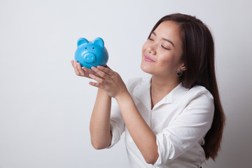 Young Asian woman kiss  a pink coin bank.