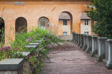 An ancient park, a concrete platform with a flower hedge and a picturesque arched passage in the background