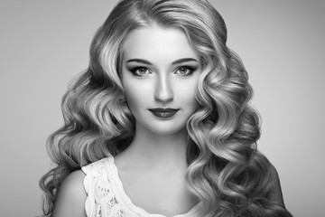Fototapeta premium Beautiful girl with long wavy and shiny hair . Blonde woman with curly hairstyle. Perfect make-up. Fashion photo. Black and White photo