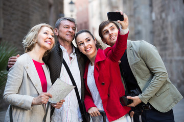 Family of four taking selfie outdoors.
