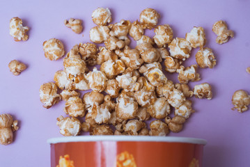 Popcorn in a paper Cup on a purple background,