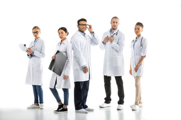 Fototapeta na wymiar Group of young confident professional doctors in white coats standing isolated on white