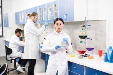 Group of young professional scientists making experiment in research laboratory