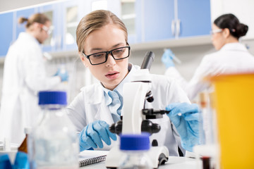 Fototapeta premium Focused young scientist working with microscope in research laboratory