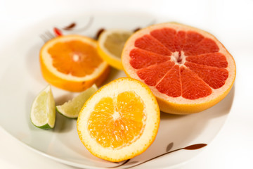Fototapeta na wymiar Fresh Lemon, Lime, Grapefruit And Orange Fruits on Top of White Porcelain Plate