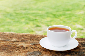 white cup of tea on a wooden table and green background