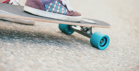 Male leg sneakers on longboard, close-up.