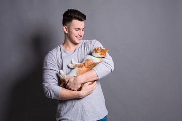 Young man with ginger cat at gray studio background