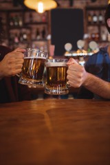 Two young men toasting their beer mugs