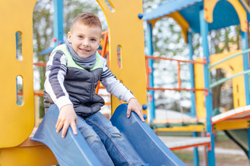 Fototapeta na wymiar Little boy play on playground with blur park background