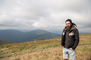 Naklejka premium bearded man on windy mountain top on natural cloudy sky