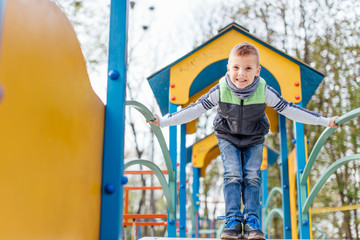 Fototapeta na wymiar Little boy play on playground with blur park background