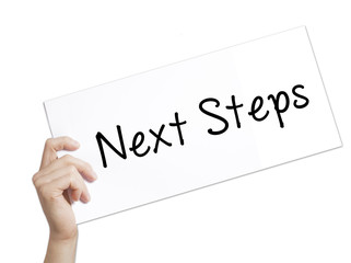 Next Steps Sign on white paper. Man Hand Holding Paper with text. Isolated on white background