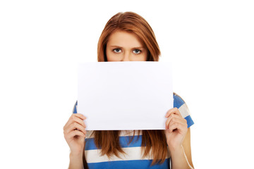 Teenage woman covering face with paper card