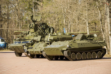 Military equipment at the exhibition. Russian tanks are standing side by side in the forest.