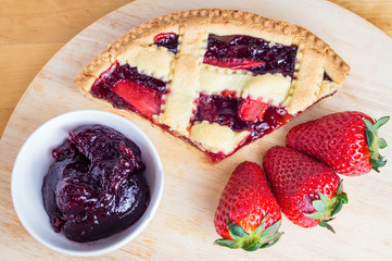slice of fresh homemade cherries tart and  strawberry on wooden table