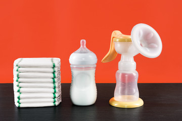 manual breast pump, baby bottle with milk. Mother care breast milk healthy food. Jar with milk in children's room breast feeding, bottle with breastmilk, diapers background