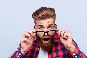 Close up portrait of shocked amazed man in checkered shirt touching his glasses