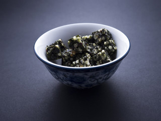 Seaweed snacks on cubes placed in Chinese bowl isolated on black background 