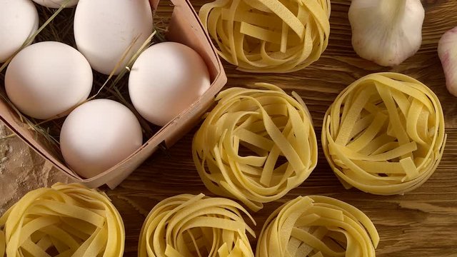 pasta, eggs, oil, tomatos, garlic and flour on wooden background