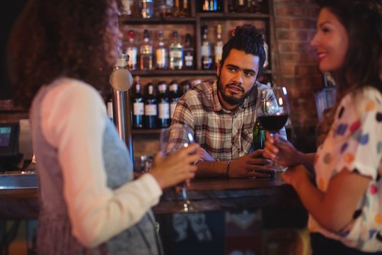 Young women interacting with bartender at counter