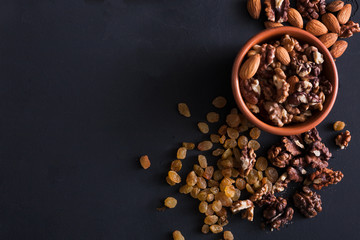 Nuts and raisins at black background. Healthy source of fat for vegans and vegetarians