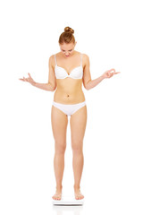 Slim shocked woman holding a scale