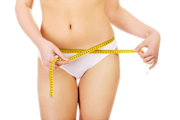 Beautiful slim woman measuring her hips