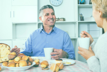 Mature couple have an afternoon snack with fresh muffins and cake