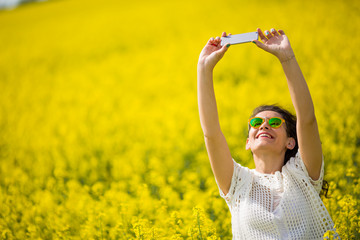 Young lovely brunette, taking selfie in rapeseed