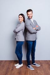 Vertical full-length photo of two businesspeople standing with crossed hands against gray background